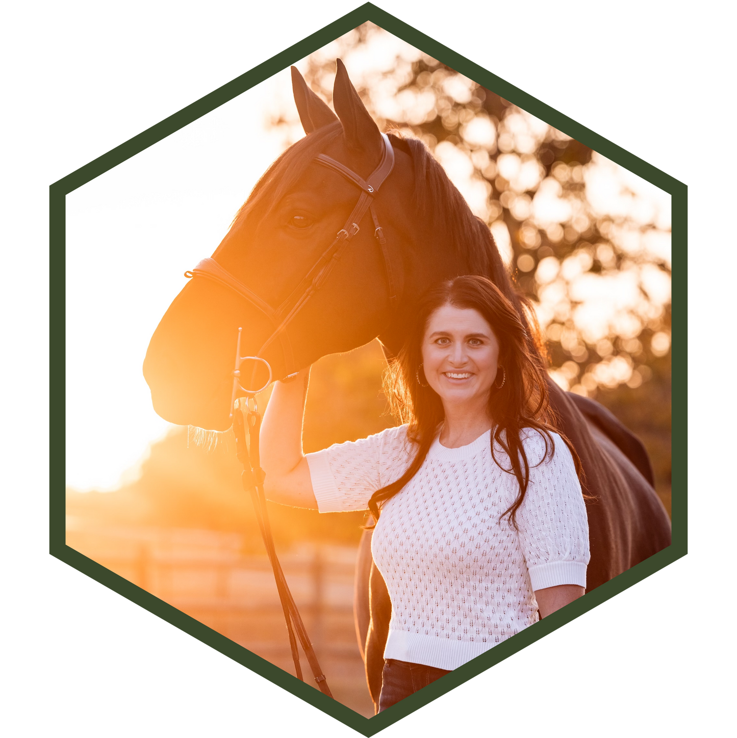 Photo of Katie standing next to a horse with a warm, blurred background